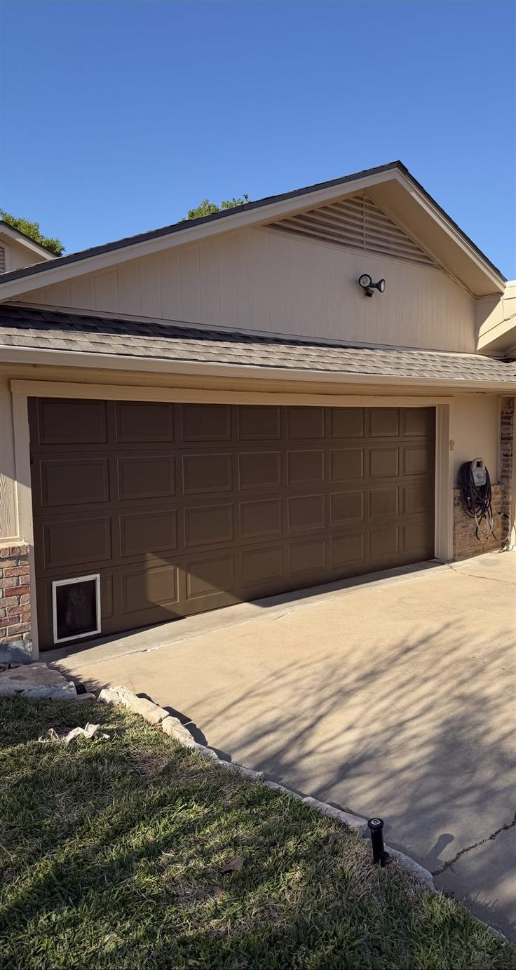Garage door and home exterior after repainting in a rich solid brown, full exterior house painting in the Brazos Valley, TX